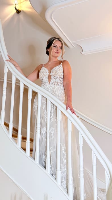 Braut im Spitzenkleid auf einer weißen geschwungenen Treppe